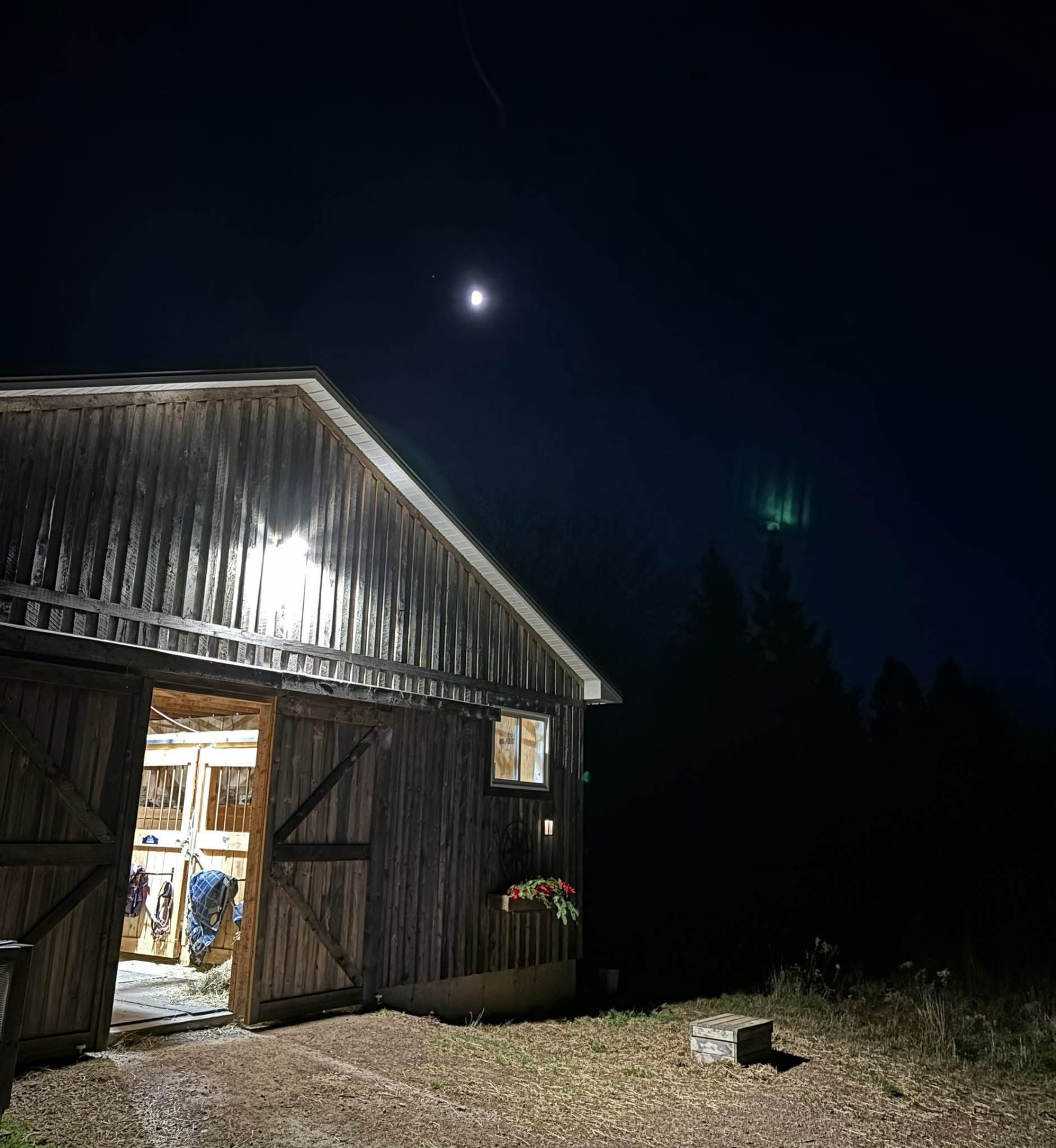 Barn at night lit by the moon with northern lights in the sky