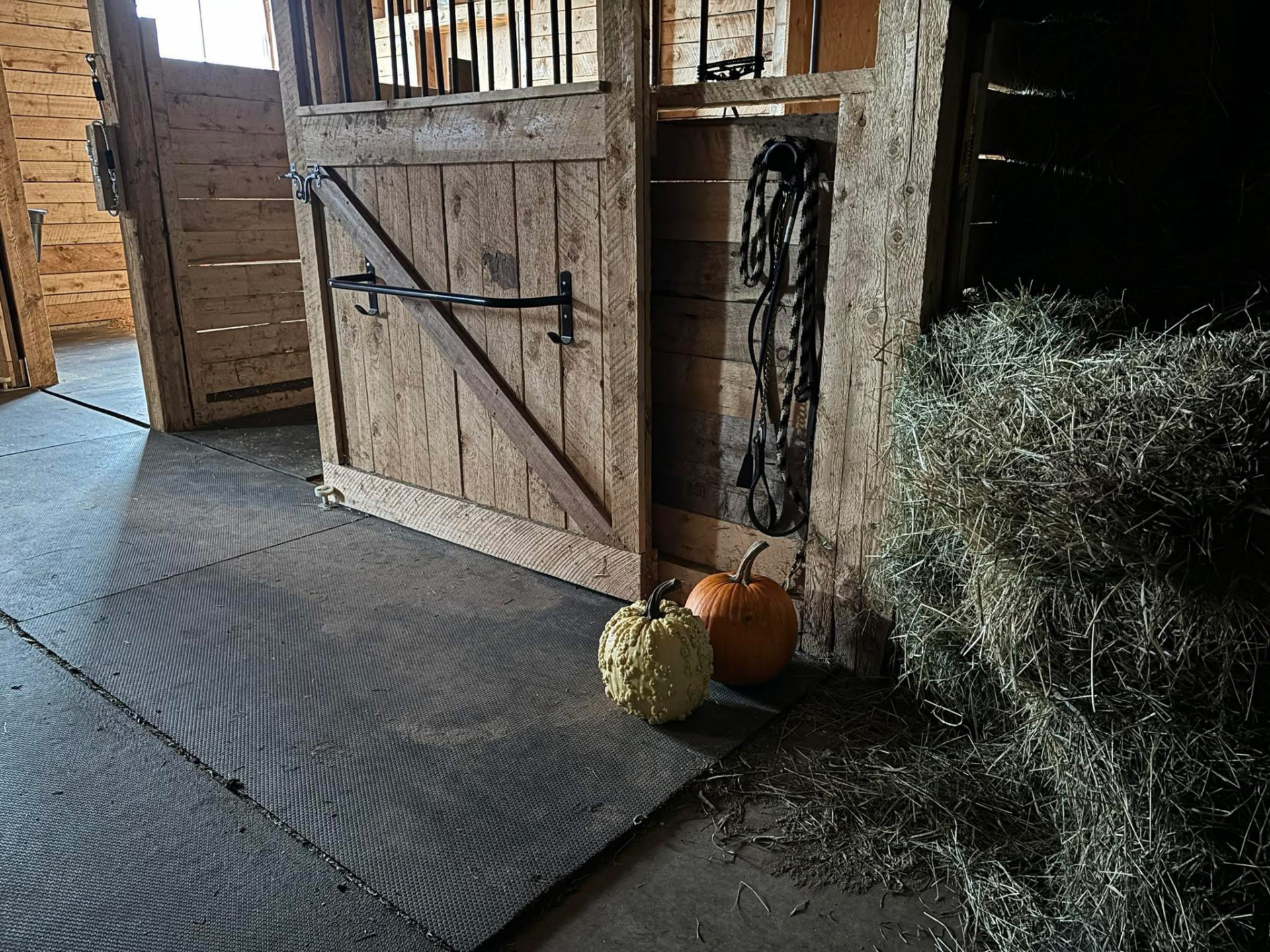 Barn stall doorway with autumn pumpkins and a hay bale